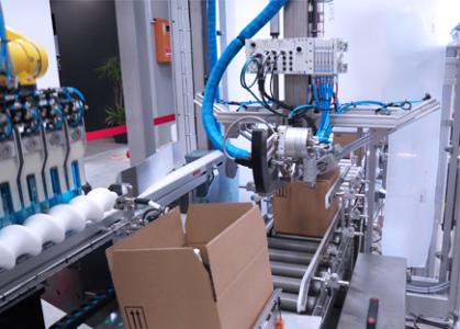 Arrivée des flacons cosmétiques dans l'encaisseuse topload JYGA